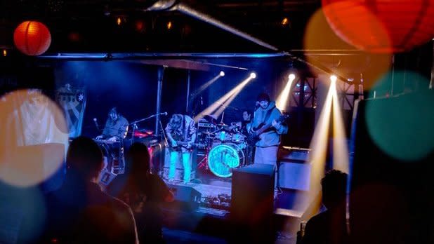 A band plays on a stage under blue light