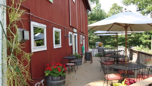 exterior of Billsboro Winery's back wooded patio with tables, chairs, and umbrellas