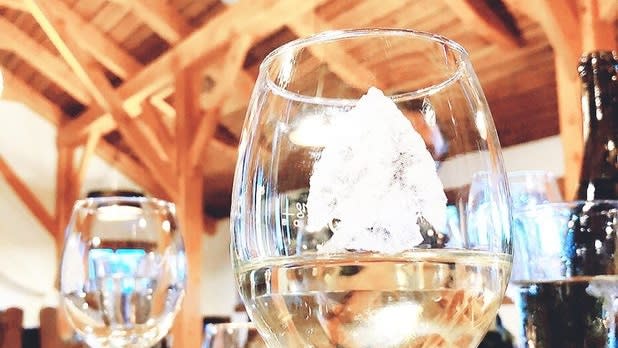 A glass of white wine sits inside the wood interior of a tasting room
