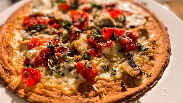Thin crust pizza decorated with white cheese and red tomatoes