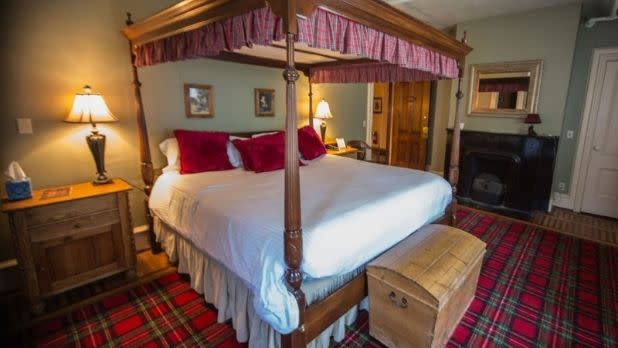 A bed and tartan-patterned rug and canopy at the Brae Loch Inn