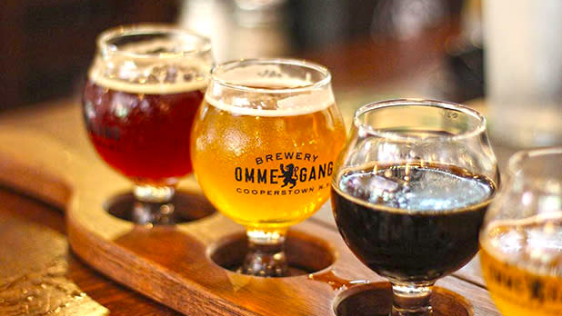 A selection of three different ales sitting in a wooden tasting palette from Brewery Ommegang