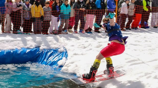 A man on a snowboard challenges the icy pond in the Slush Cup event at the Bristol Mountain Spring Carnival