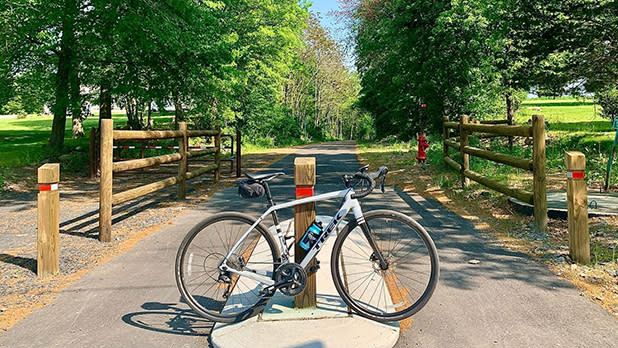 A bike leans against a wooden post along the tree-lined Goshen Heritage Trail