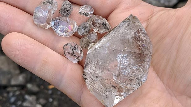 A man holds a handful of quartz crystals from the Herkimer Diamond Mines