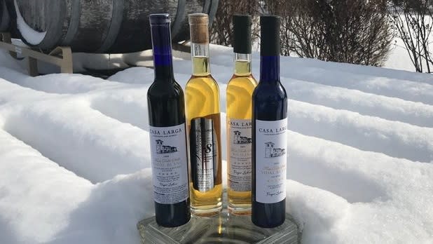 Two bottles of white "ice wine" sit in between two bottles of red winein the snow
