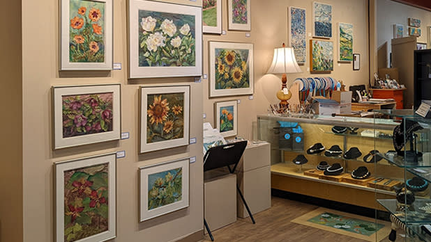 Paintings hanging on a wall and a jewelry display case inside a boutique.