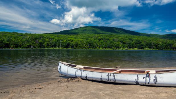 Canoe sitting on the shore of a lake overlooking mountains