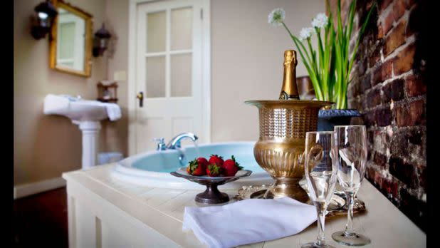 Interior of hotel room showing jacuzzi and champagne glasses and plate of strawberries dipped in chocolate