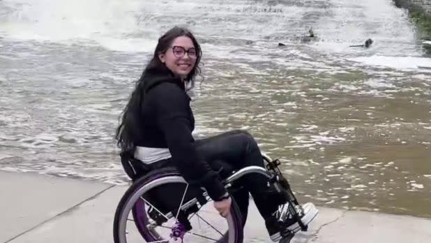 Woman in a wheelchair posing next to a waterfall