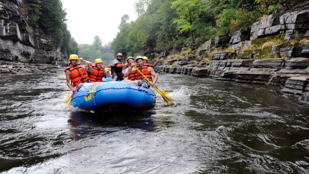 Group of people rafting on calm rapids with rock formations surrounding them