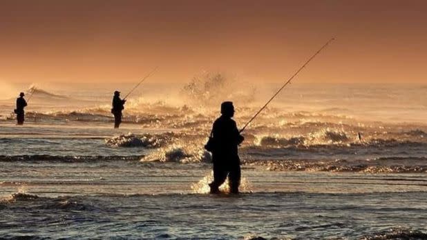 men standing in ocean fishing
