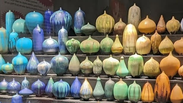 Blue, green, yellow, and orange ceramic bottles on display
