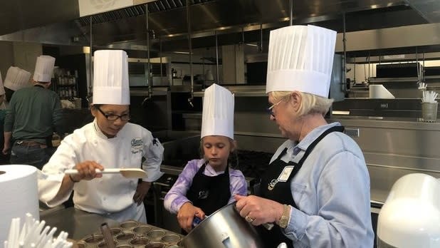 A chef teaching a woman and a girl to cook