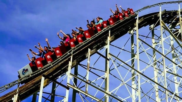 A red roller coaster races down wooden tracks
