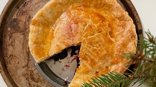 A grape pie in a tin with one slice missing