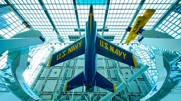 Blue airplane with U.S. Navy yellow lettering suspended inside the Cradle of Aviation Museum