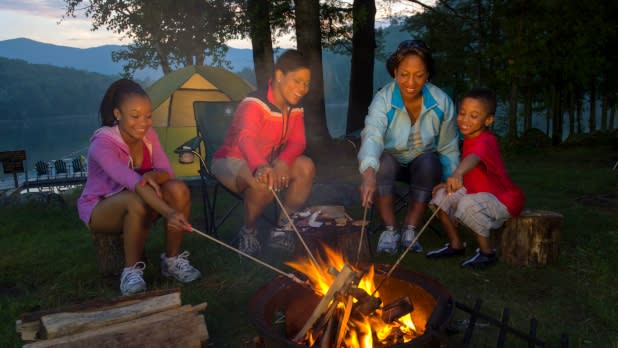 A family roasting marshmallows over a campfire on a camping trip in Adirondacks
