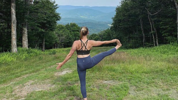 A woman doing yoga looking out at the Catskill Mountains