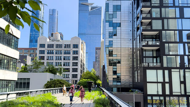 People stroll along the elevated platform through the cityscape on the High Line