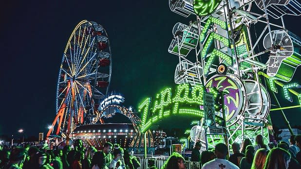 Neon lights from various midway rides glow at night at the Great New York State Fair