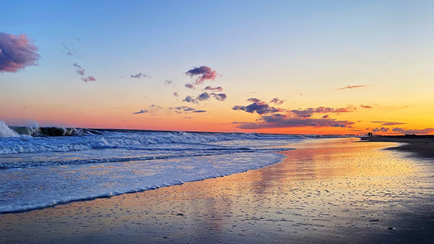 Waves crash onto the sun amid a colorful sunset in Long Beach