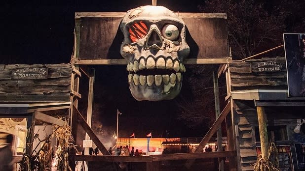 A massive skull hangs over the entryway of Double M Haunted Hayrides