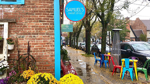 Potted yellow mums and colorful patio furniture outside Samuel's Sweet Shop in Rhinebeck