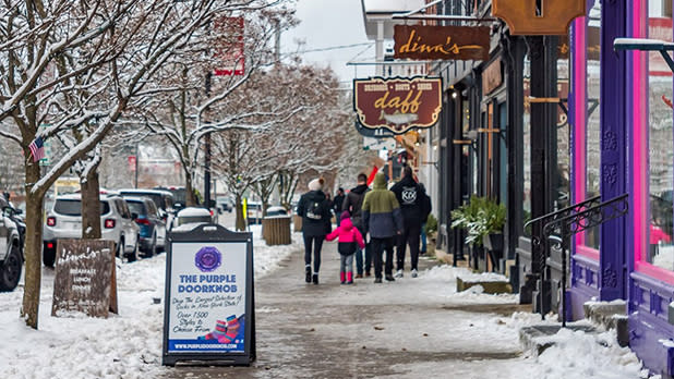 A family strolls on a snowy shop-lined main street