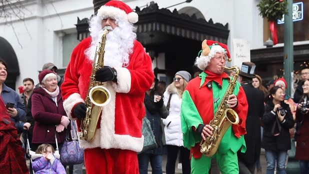 A saxophone-playing Santa and elf delight crowds at the Troy Victorian Stroll