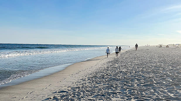 People walking on the shoreline at a beach on Fire Island in Long Island, NY.