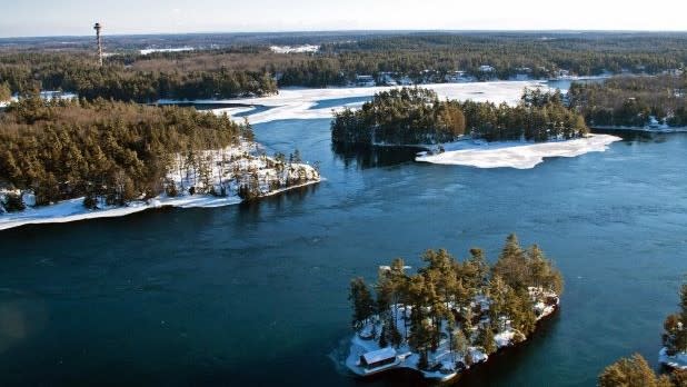 Aerial view of the Thousand Islands-Seaway in winter with tree-covered islands scattered across the icy surface of a river.