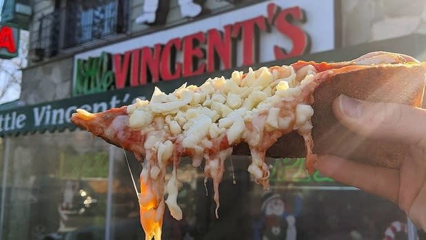 A slice of "cold cheese pizza" being held up in front of Little Vincent's