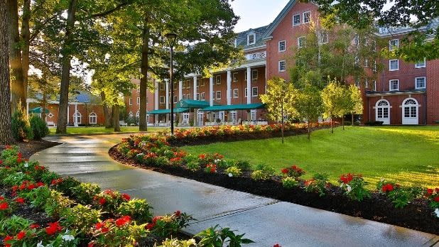 A shrubbery-lined walkway leads to the Gideon Putnam hotel