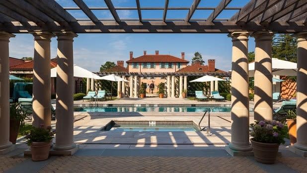View of the Tuscan-inspired Glenmere Mansion with an in-ground pool and hot tub in New York's Hudson Vallley