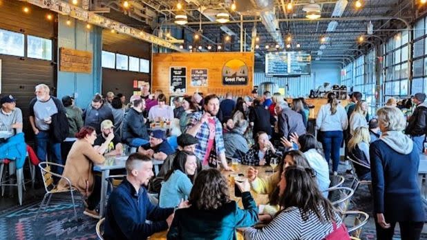 People sitting at tables at an indoor brewery