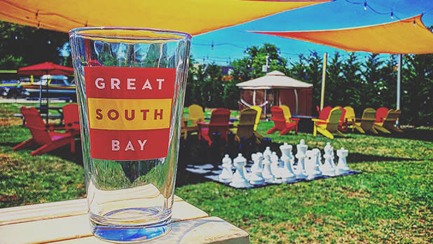 An empty pint glass sits on a table with a lifesize chess board in the background at Great South Bay Brewery