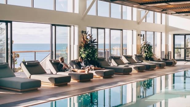 Two people relaxing on lounges by the pool in the Bath House at Gurney's Montauk Resort on Long Island