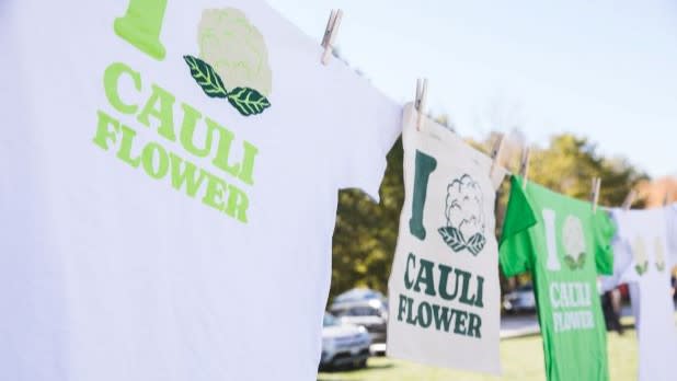 t-shirts and other merch with "I (image of cauliflower) Cauliflower" printed on the front hang on a clothesline at the Margaretville Cauliflower Festival.