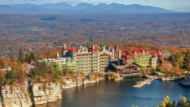 View of Mohonk Mountain House surrounded by fall colors with the Catskill Mountains in the distance