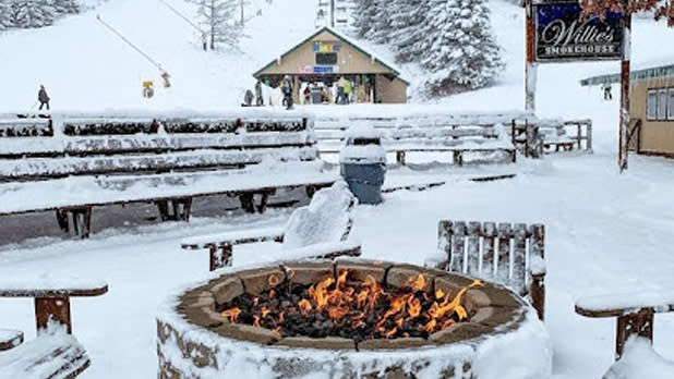 View from sitting at a snowy fire pit looking up at a ski lift