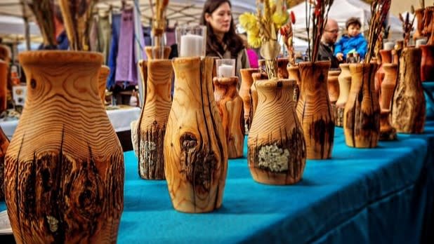 Rows of wooden vases sitting on a turquoise table cloth