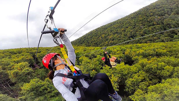 Two people riding along the hunter mountain zip line above the Hunter mountain forests