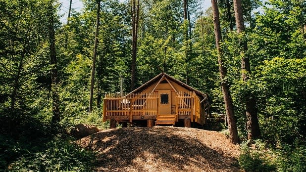 A luxury glamping tent on a raised deck in the Adirondack forest at Huttopia