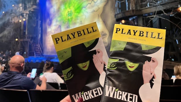 Two Playbills for "Wicked" held up in front of a stage
