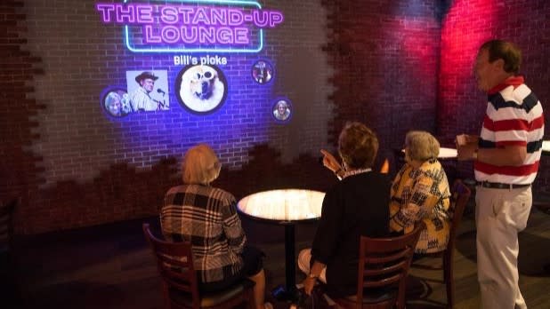 a group of people laughing while sitting down at a table in the Stand Up Lounge at the National Comedy Center