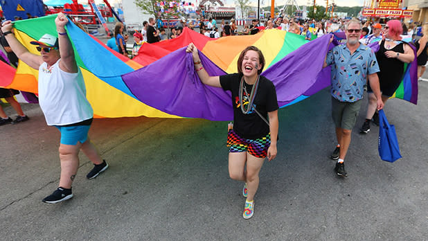 People hold a large Pride flag at a march during Pride Day at the New York State Fair