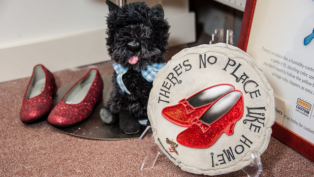 Ruby red slippers, a commemorative plate, and stuffed Toto toy on display at the All Things Oz Museum