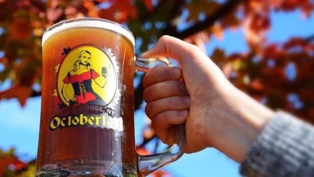 A hand holding a mug of beer that reads "Lake George, NY Oktoberfest"