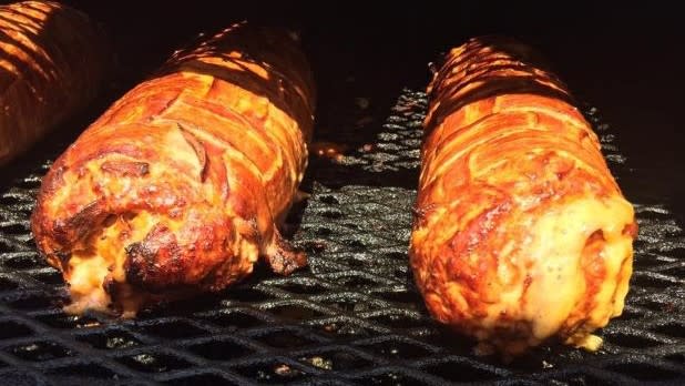 The main ingredients of the Bacon Bomb sandwich cooking on a grate in a smoker.